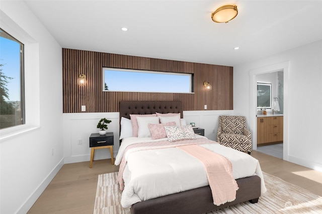 bedroom featuring ensuite bath and light hardwood / wood-style flooring