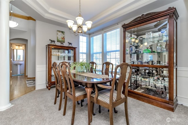 dining space featuring sink, a chandelier, light carpet, ornamental molding, and a raised ceiling