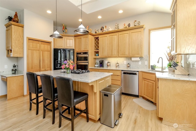 kitchen with sink, tasteful backsplash, light brown cabinets, a kitchen island, and black appliances