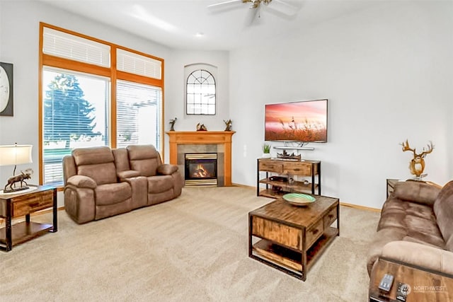 living room featuring a tiled fireplace, light colored carpet, and ceiling fan