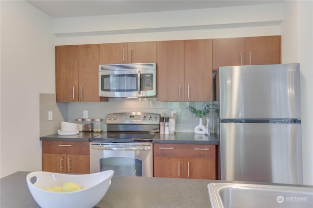 kitchen with tasteful backsplash, appliances with stainless steel finishes, and sink