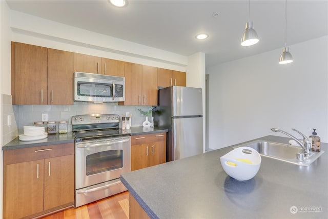 kitchen featuring sink, tasteful backsplash, light wood-type flooring, pendant lighting, and stainless steel appliances