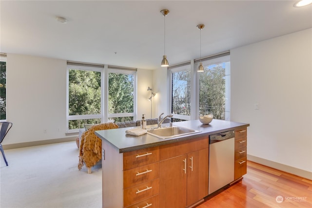 kitchen featuring pendant lighting, sink, light hardwood / wood-style flooring, dishwasher, and an island with sink