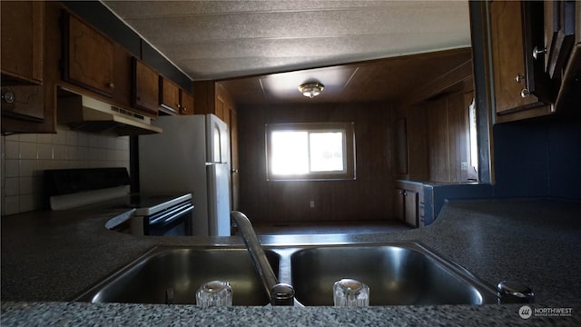 kitchen featuring backsplash, white refrigerator, sink, and electric range