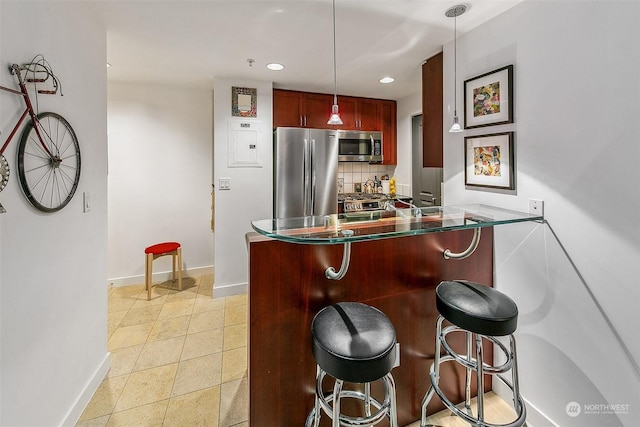 kitchen with pendant lighting, a breakfast bar area, appliances with stainless steel finishes, tasteful backsplash, and kitchen peninsula