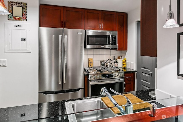 kitchen featuring pendant lighting, decorative backsplash, electric panel, and appliances with stainless steel finishes