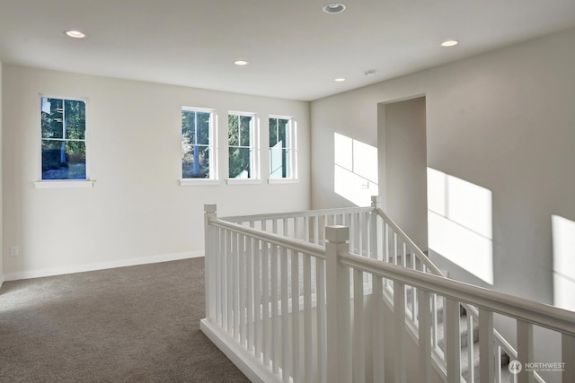 hall with dark colored carpet