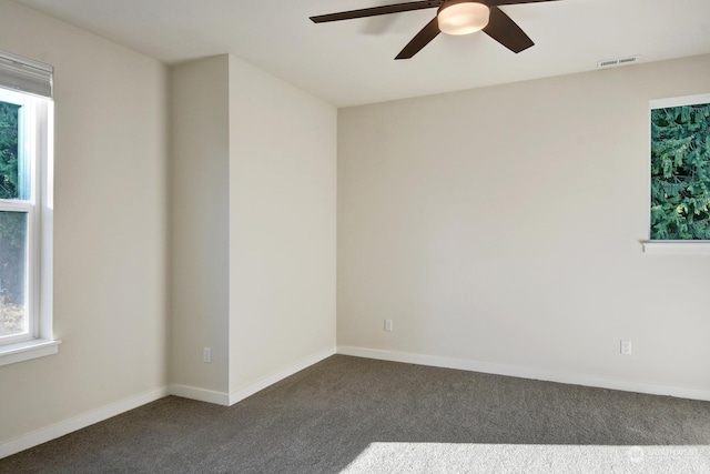 empty room with ceiling fan and dark colored carpet
