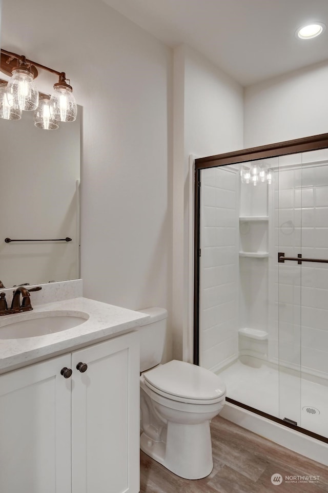 bathroom with a shower with door, vanity, hardwood / wood-style flooring, and toilet