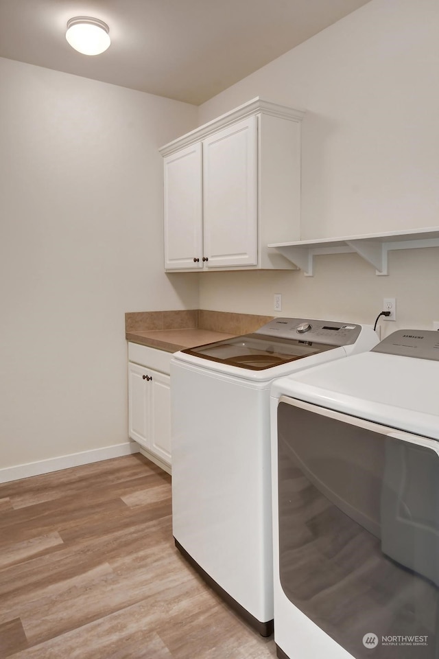 laundry area featuring cabinets, separate washer and dryer, and light wood-type flooring