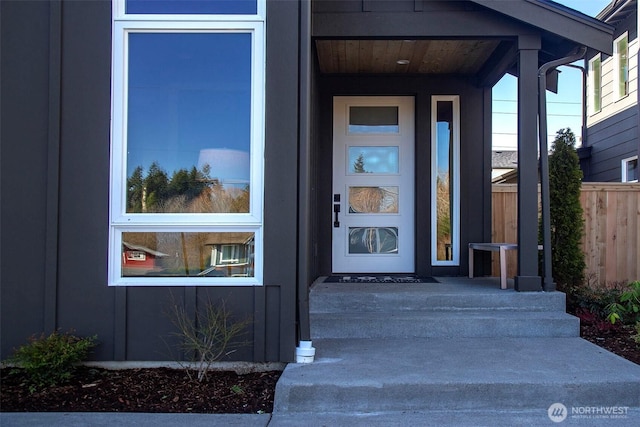 property entrance with covered porch and fence