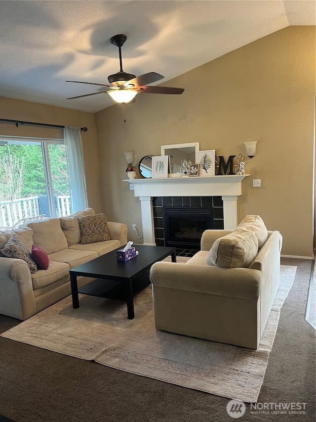 living area featuring lofted ceiling, carpet, ceiling fan, and a tiled fireplace