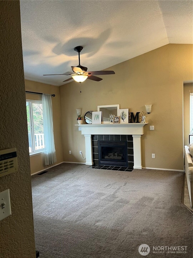 unfurnished living room featuring visible vents, a tiled fireplace, vaulted ceiling, a textured ceiling, and carpet flooring