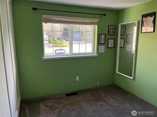 carpeted spare room featuring visible vents