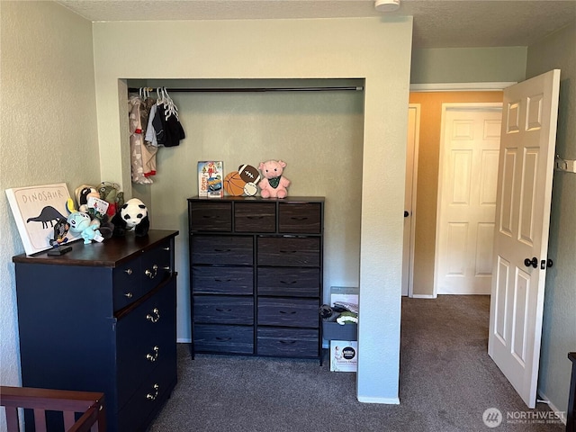 bedroom featuring baseboards, dark colored carpet, and a textured ceiling