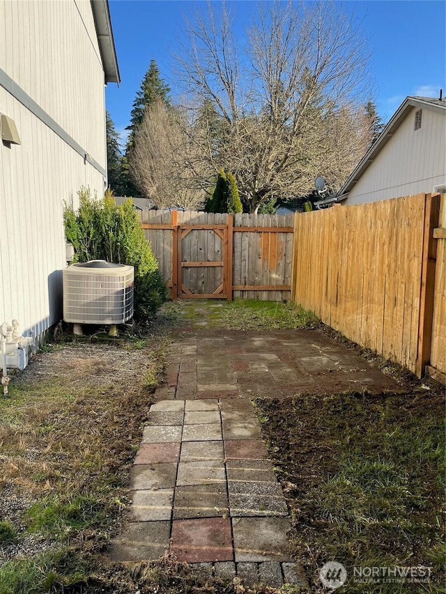 view of yard with fence, central AC unit, and a patio