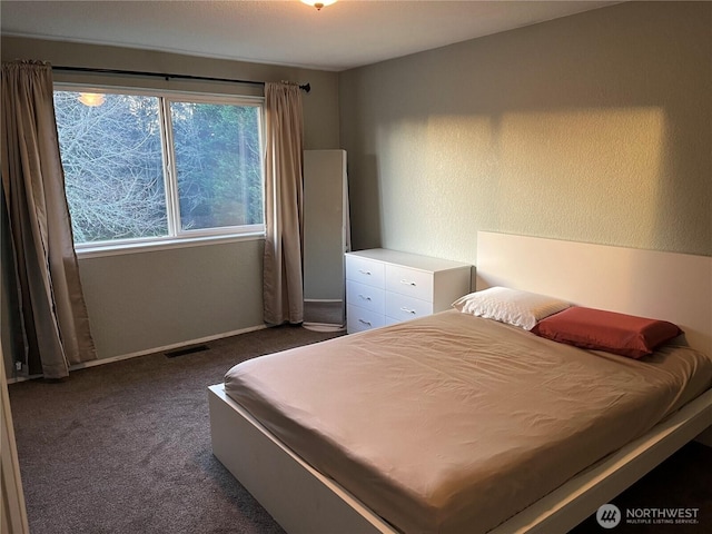 bedroom with dark colored carpet, multiple windows, and visible vents