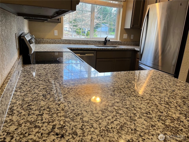 kitchen featuring light stone counters, appliances with stainless steel finishes, extractor fan, and a sink