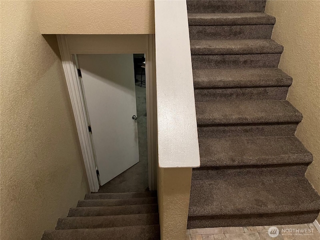 staircase featuring a textured wall