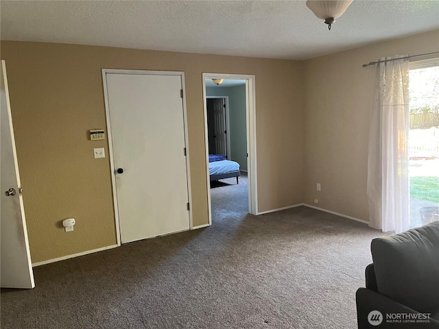 interior space featuring carpet, a textured ceiling, and baseboards