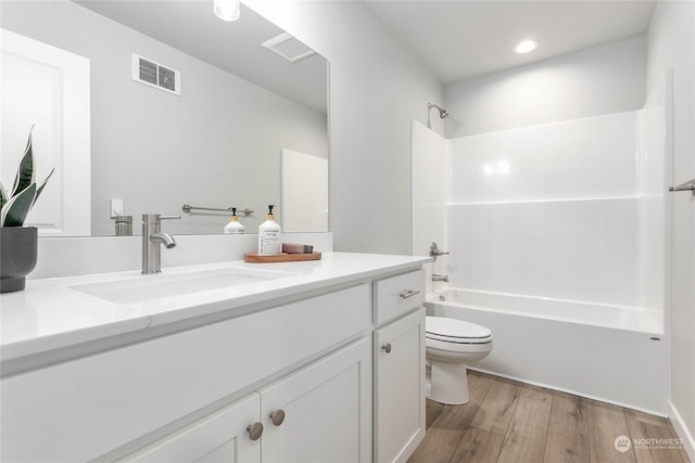 full bathroom featuring vanity, hardwood / wood-style floors, toilet, and washtub / shower combination