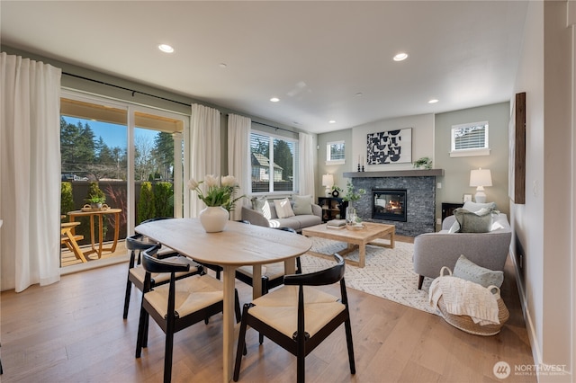 dining area with a stone fireplace, recessed lighting, and light wood-style floors