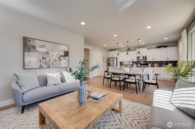 living area with light wood-style flooring, recessed lighting, and baseboards