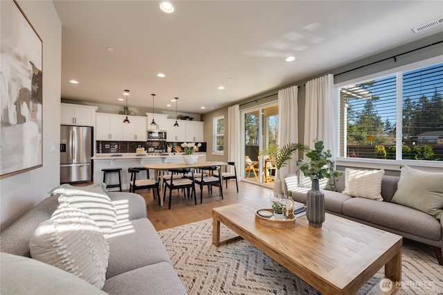 living room with recessed lighting, visible vents, and light wood-style flooring