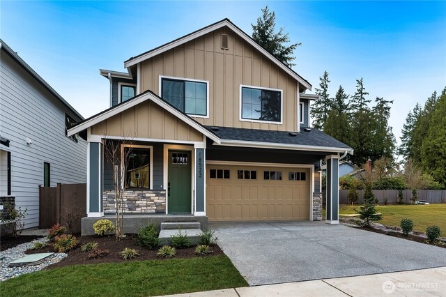 view of front facade with stone siding, board and batten siding, driveway, and fence