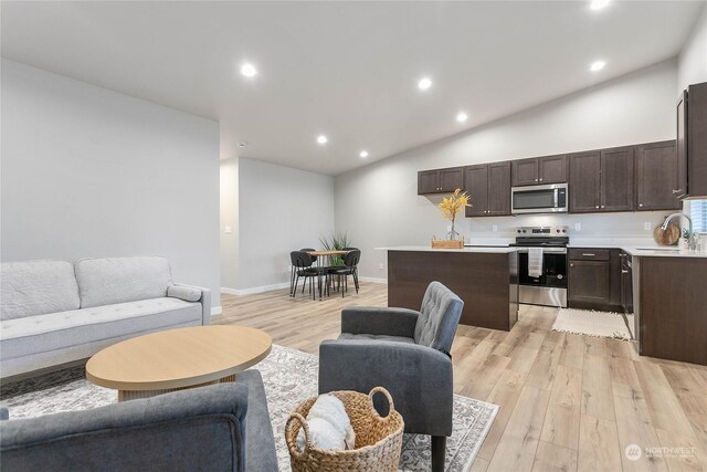 living room featuring sink, light hardwood / wood-style flooring, and high vaulted ceiling