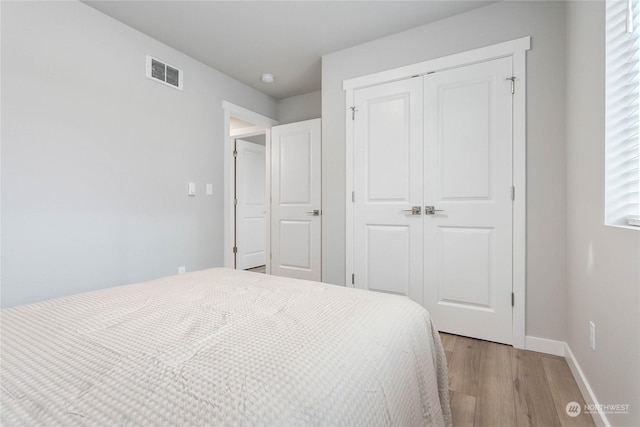 bedroom with light hardwood / wood-style floors and a closet