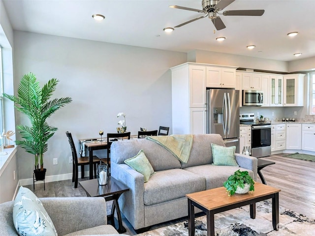 living room with ceiling fan and light hardwood / wood-style flooring