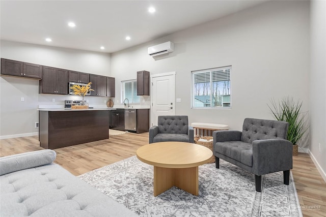 living room featuring a towering ceiling, a wall mounted air conditioner, and light wood-type flooring