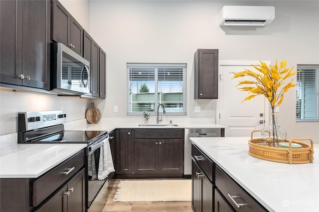 kitchen featuring dark brown cabinets, stainless steel appliances, sink, and a wall unit AC