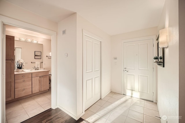 corridor featuring sink and light tile patterned flooring