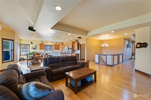 living room with an inviting chandelier, a tray ceiling, and light hardwood / wood-style flooring