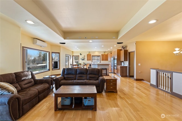 living room featuring light wood-type flooring, a wall mounted AC, an inviting chandelier, and a tray ceiling