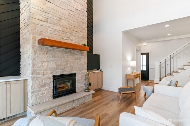 living room featuring a fireplace, light hardwood / wood-style flooring, and a high ceiling