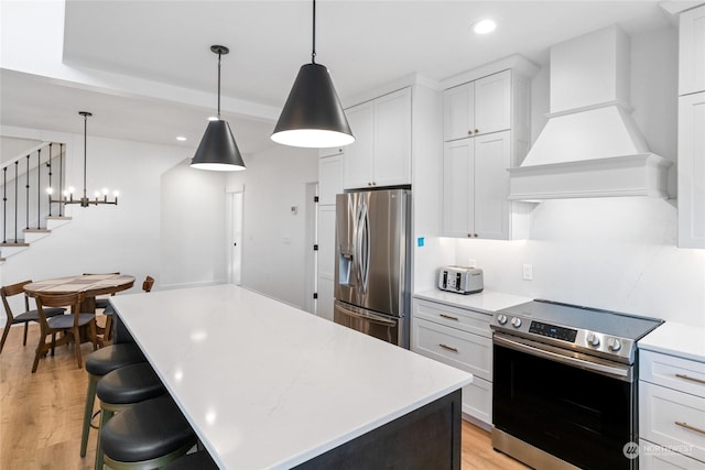 kitchen featuring white cabinetry, pendant lighting, custom exhaust hood, and appliances with stainless steel finishes