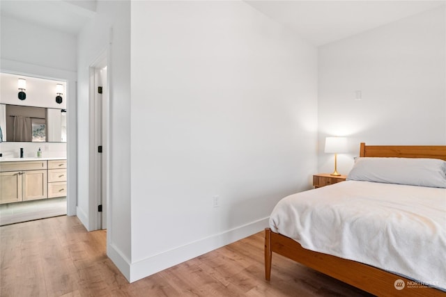 bedroom with connected bathroom and light wood-type flooring