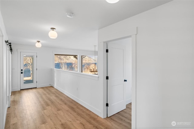 entrance foyer with a barn door and light hardwood / wood-style flooring