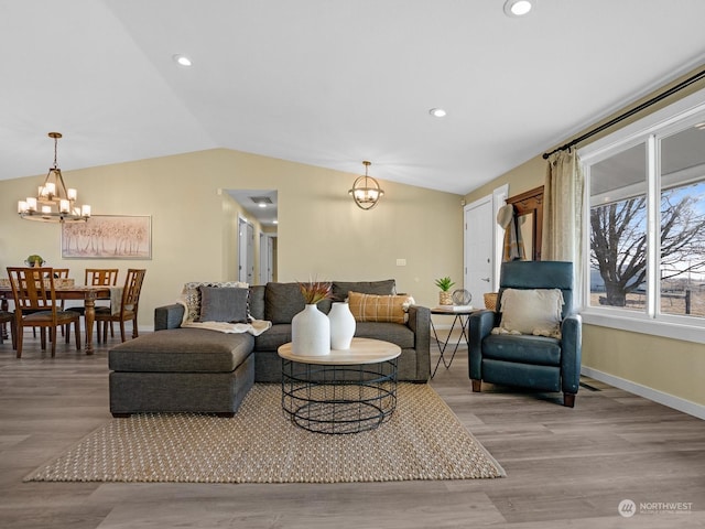 living room featuring vaulted ceiling, an inviting chandelier, and light hardwood / wood-style floors