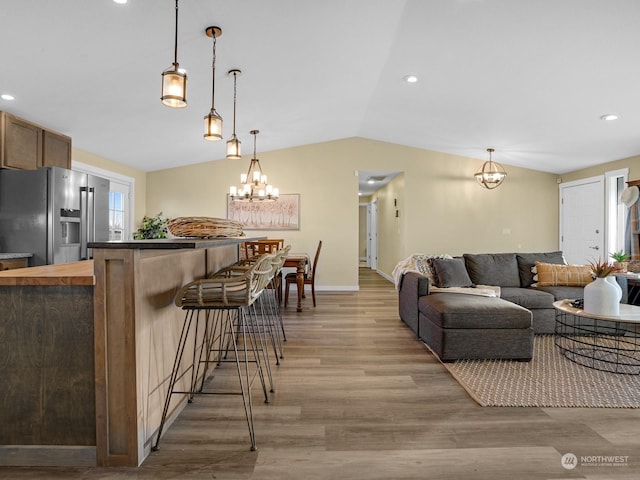 living room with light hardwood / wood-style flooring, vaulted ceiling, and a chandelier