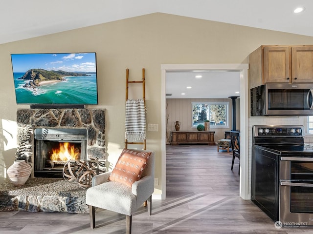 living room with lofted ceiling, hardwood / wood-style floors, and a fireplace