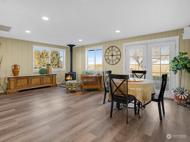 dining space with light hardwood / wood-style flooring, french doors, and a wood stove