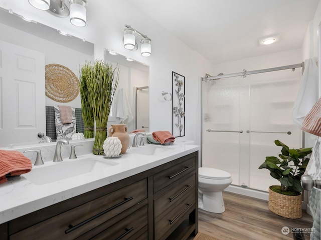 bathroom featuring an enclosed shower, vanity, hardwood / wood-style flooring, and toilet