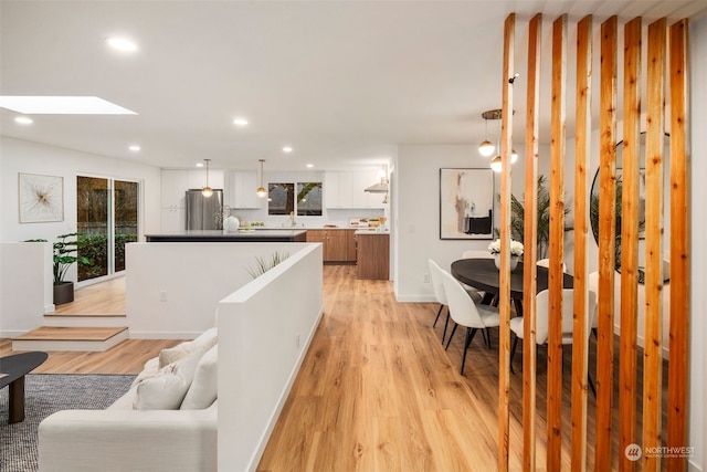 living room with sink, light hardwood / wood-style floors, and a skylight