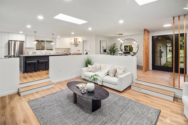 living room with a skylight and light hardwood / wood-style flooring