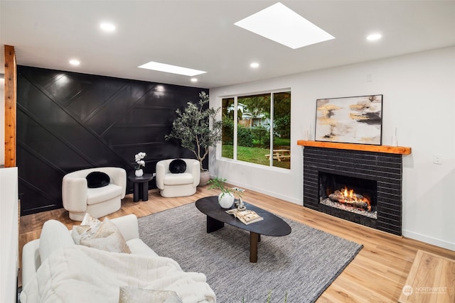 living room with hardwood / wood-style floors, a fireplace, and a skylight