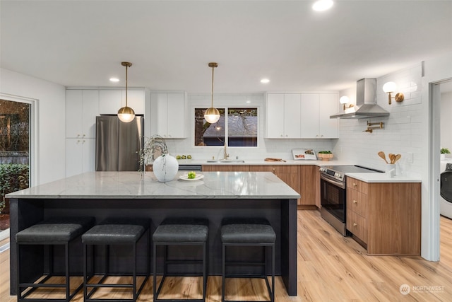 kitchen featuring stainless steel appliances, a center island, white cabinets, and wall chimney exhaust hood